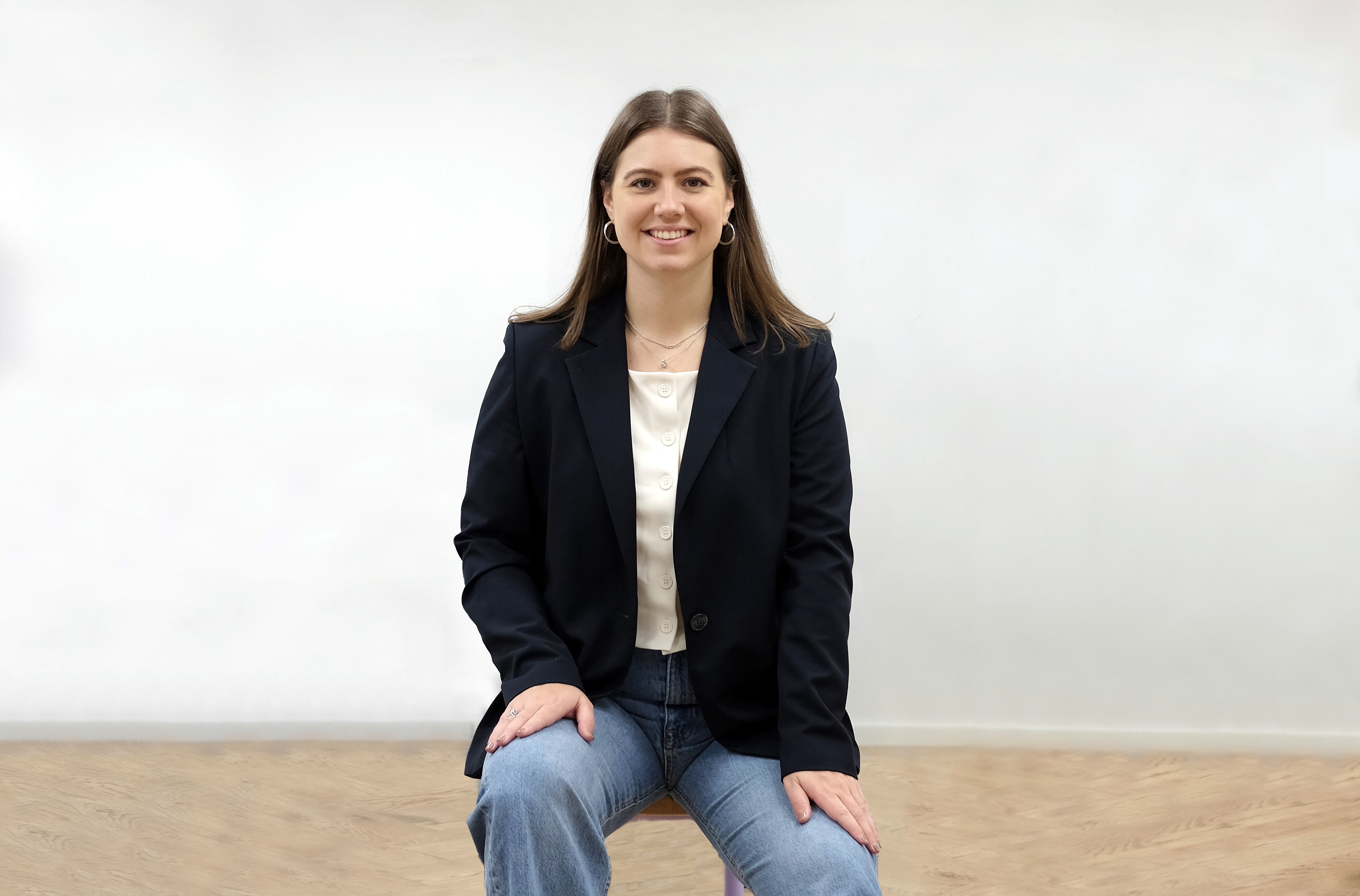 Lisa-Marie sitzt in der Mitte von einem hellen Raum auf einem Stuhl, ist aufgerichtet und schaut wach in die Kamera