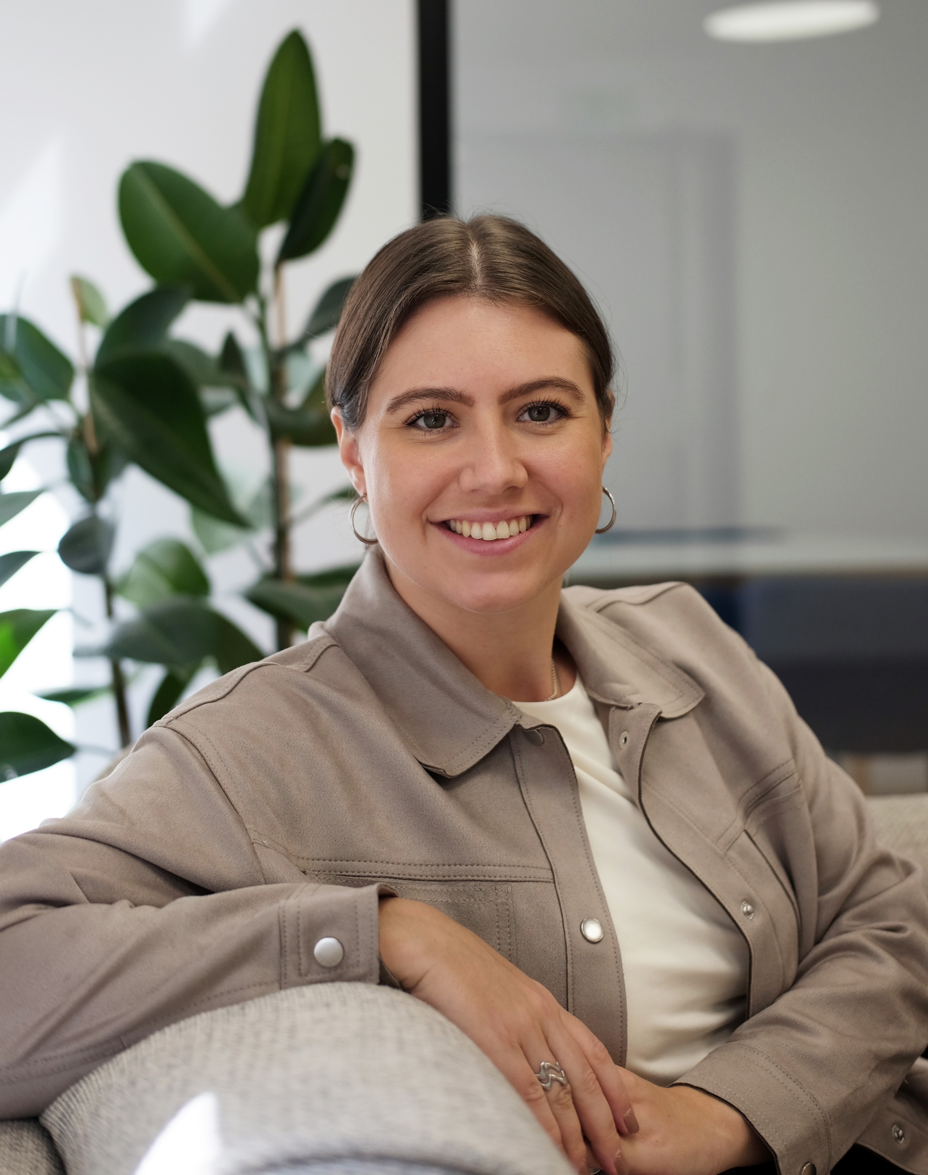 Lisa-Marie sitzt auf einer Couch, ist der Kamera schräg zugewandt und lächelt